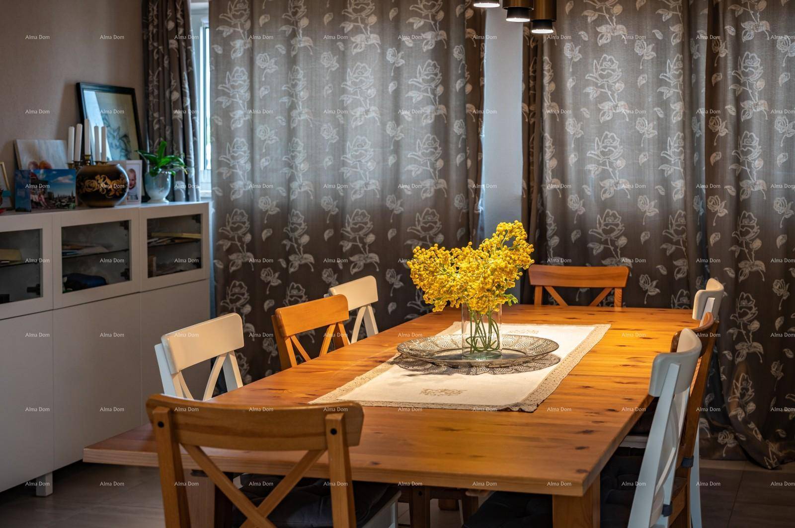 Gemütlicher Essbereich mit Holztisch, verschiedenen Stühlen und floralen Vorhängen.