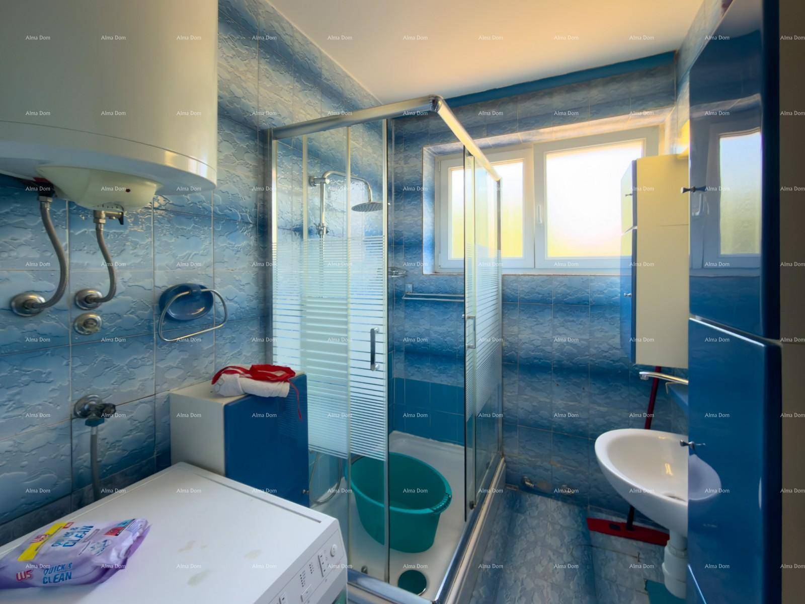 Badezimmer mit blauen Fliesen, Duschkabine, Waschbecken und Waschmaschine.