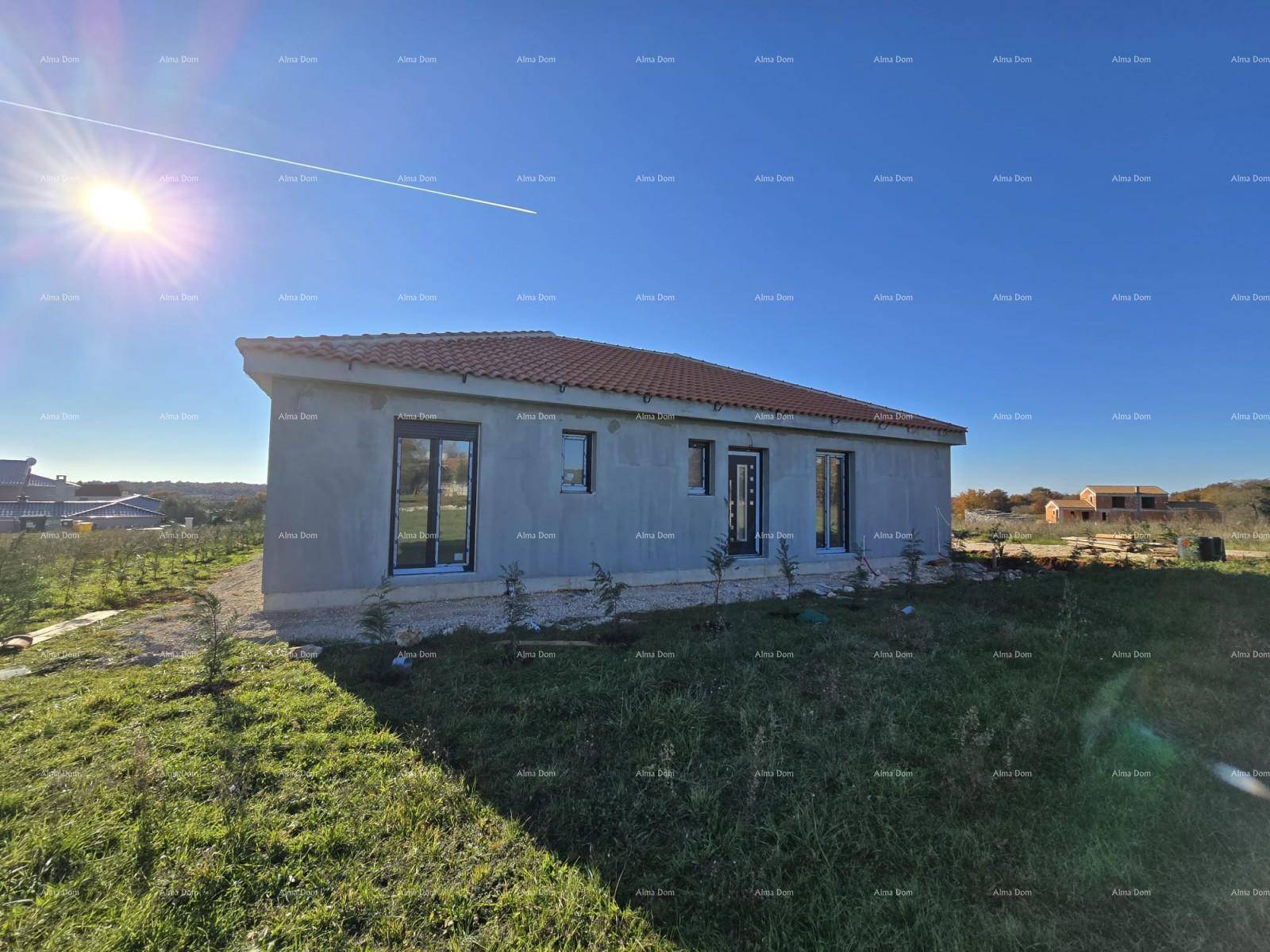 Neubau-Einfamilienhaus im Rohbauzustand mit Ziegeldach und grüner Wiese unter strahlendem Sonnenschein.