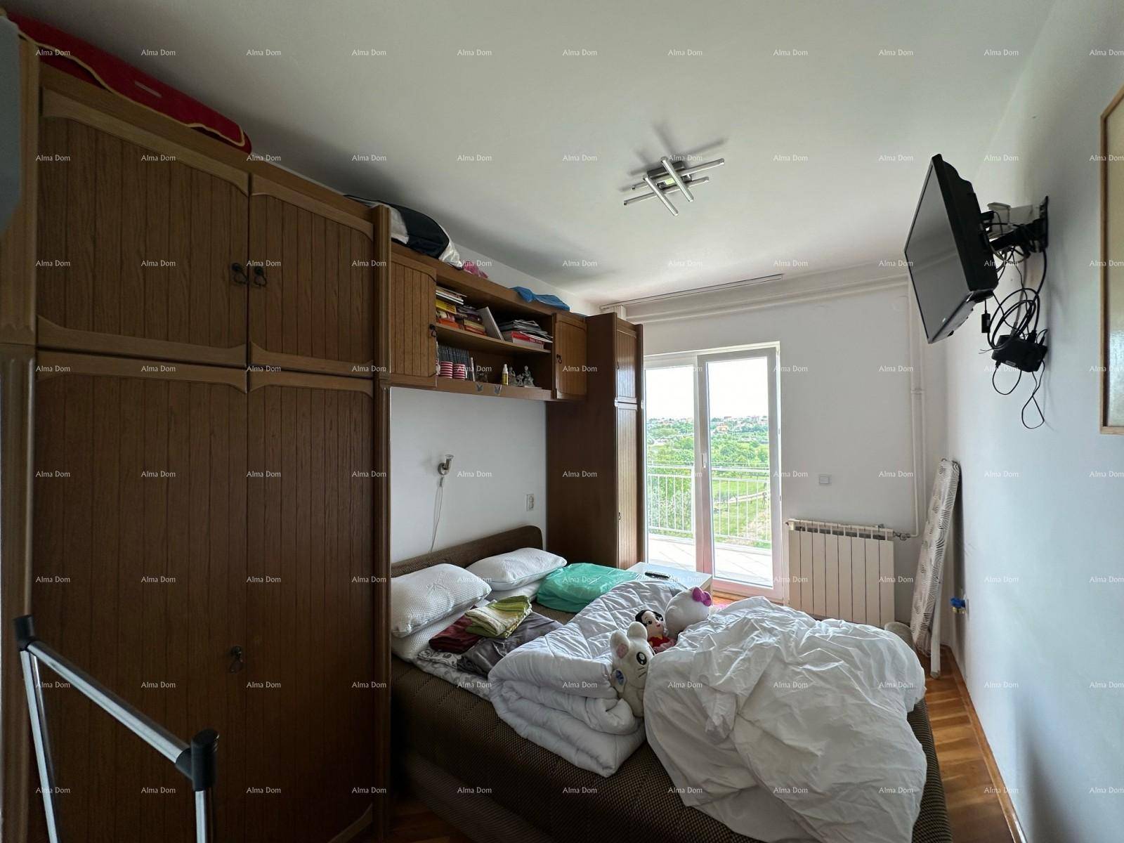 Schlafzimmer mit Holzkleiderschrank, Bett und Wandfernseher sowie Balkonzugang.