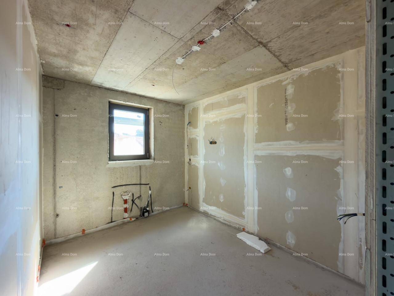 Kleiner unfertiger Raum mit einem Fenster, sichtbaren Installationen und Betonoberflächen.