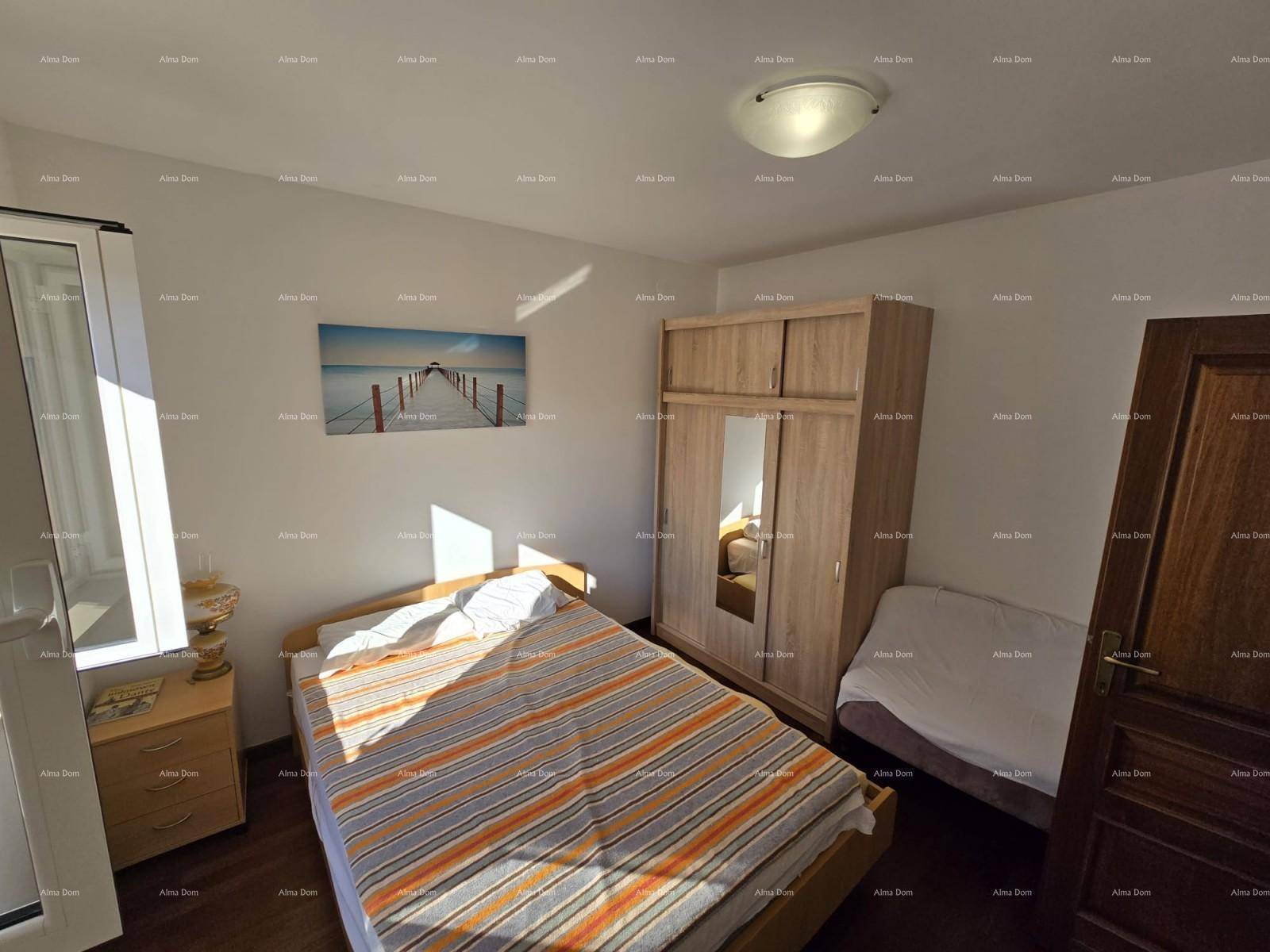 Helles Schlafzimmer mit Doppelbett, Holzschrank und dunklem Laminatboden.