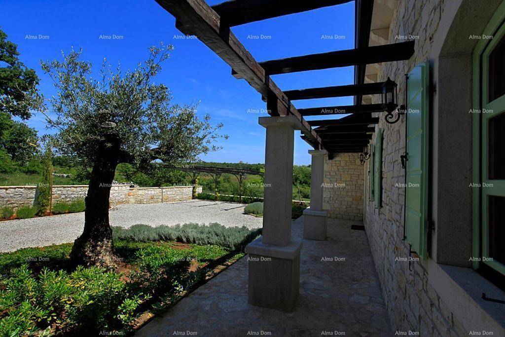 Seitenansicht der Steinvilla mit Pergola, Kiesauffahrt und mediterraner Bepflanzung.
