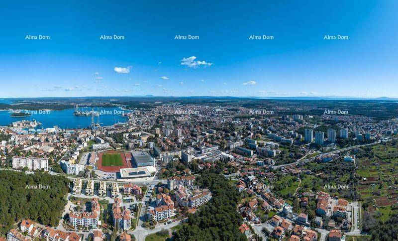 Panoramablick auf eine weitläufige Küstenstadt mit Hafen, Wohngebieten und viel Grün.