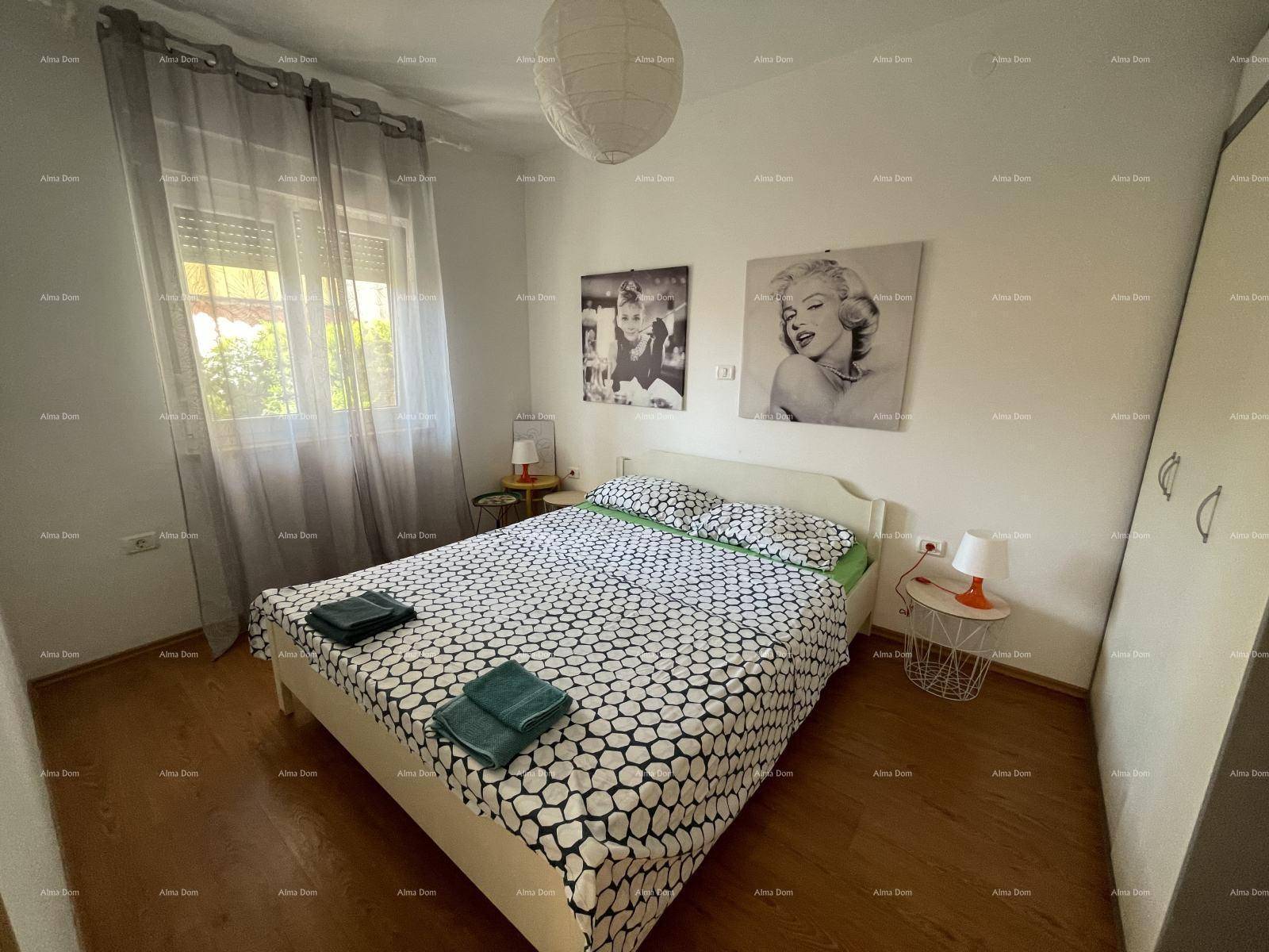 Schlafzimmer mit Doppelbett, Holzboden und Fenster, dekoriert mit Pop-Art-Bildern.