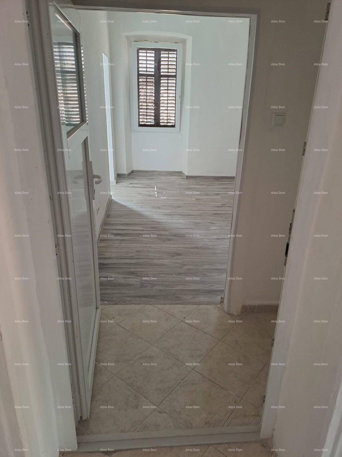 Flur mit Fliesenboden, der zu einem hellen Zimmer mit Laminatboden führt.