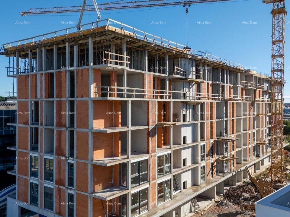 Luftaufnahme des im Bau befindlichen Gebäudes mit sichtbarer Betonstruktur und Ziegelwänden unter blauem Himmel.