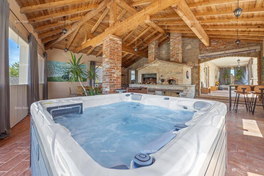 Großer Innenbereich mit Whirlpool, Holzbalkendecke und traditionellem Kamin.