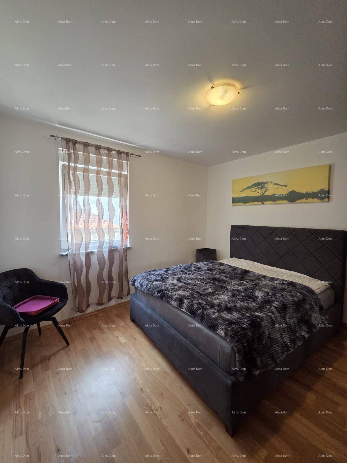 Schlafzimmer mit Doppelbett, Holzboden und einem Fenster mit gemusterten Vorhängen.