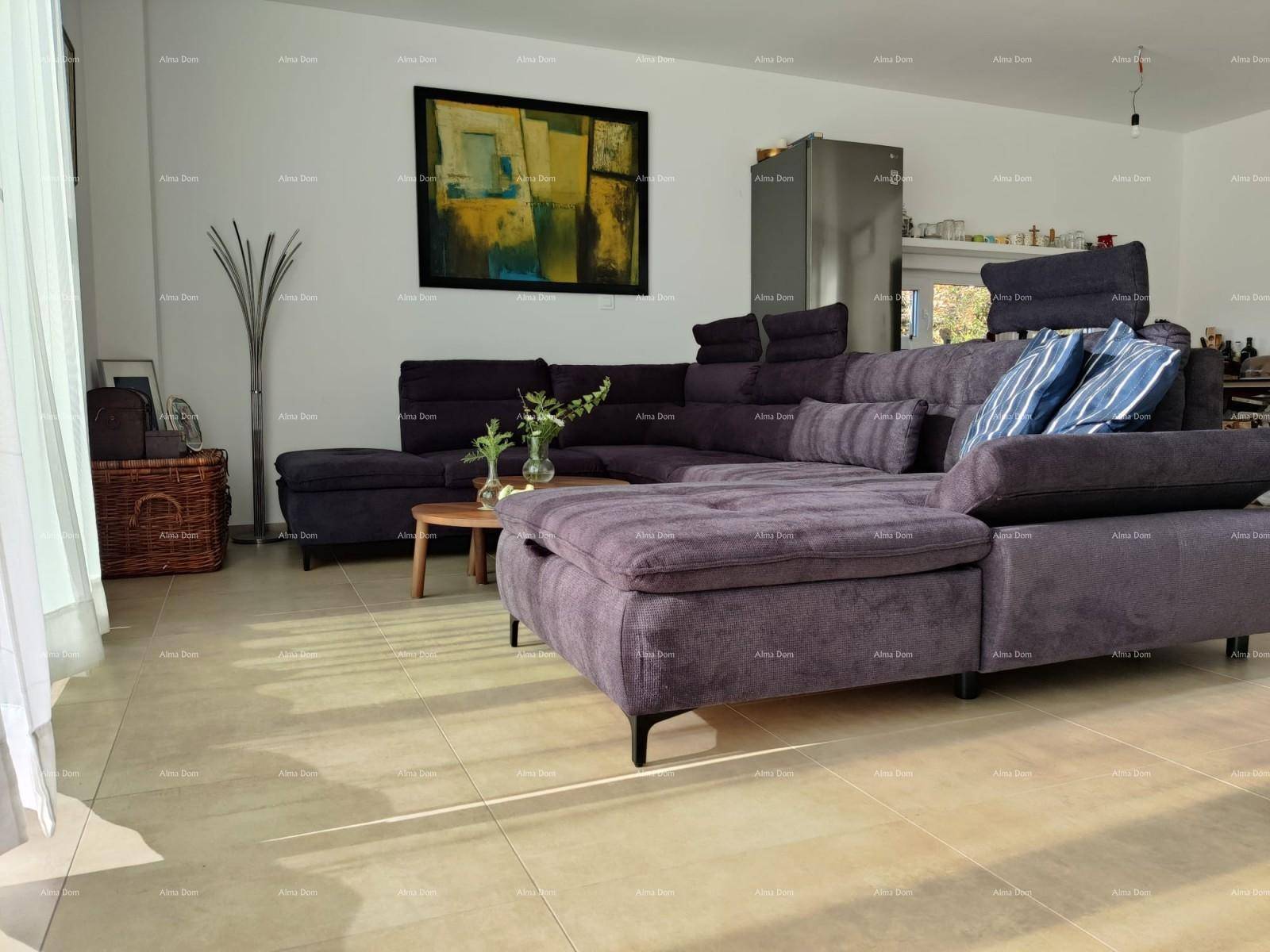 Gemütlicher Wohnbereich mit großem Ecksofa, Kunstwerk an der Wand und Zugang zum Außenbereich.