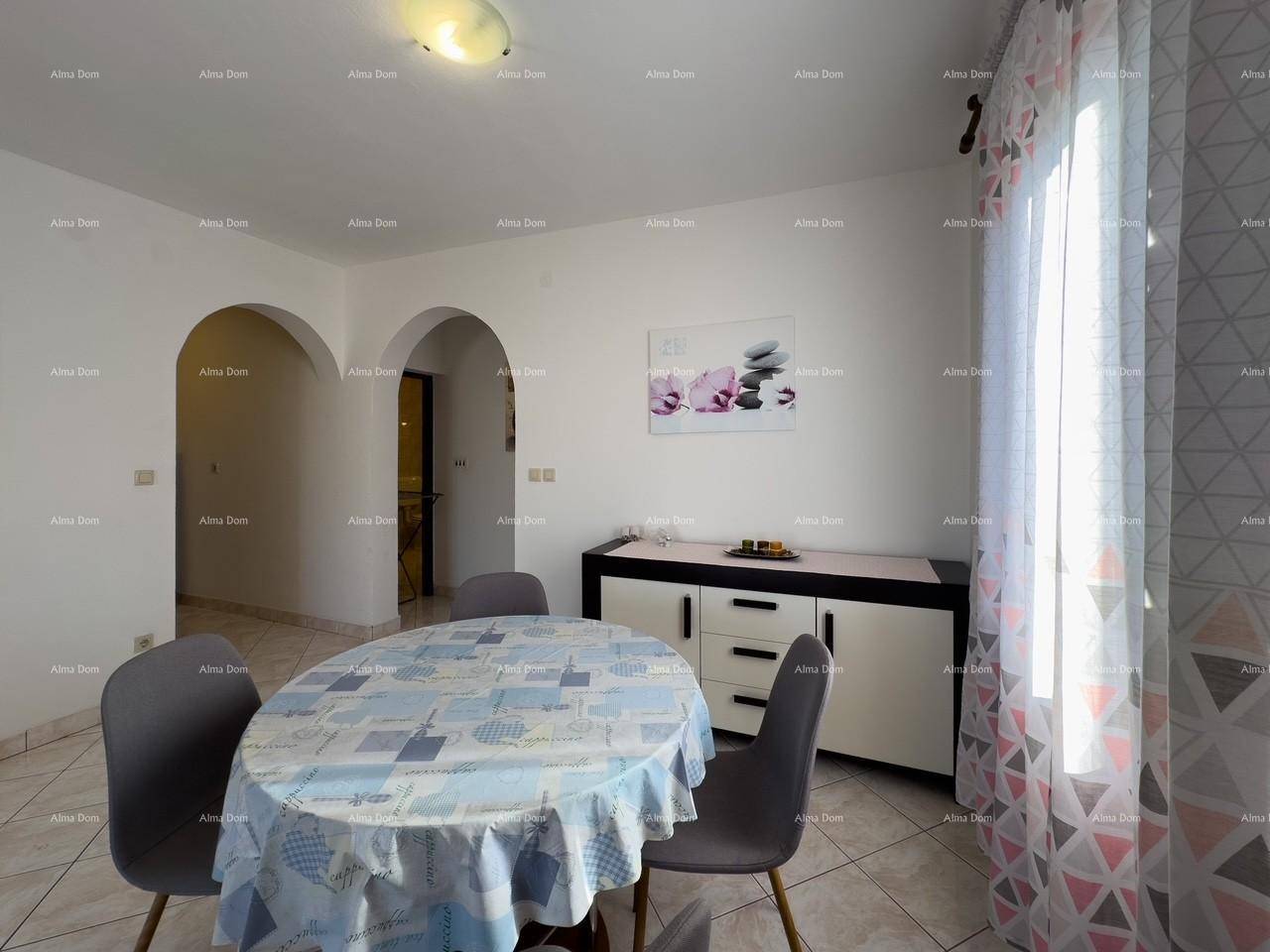 Detailansicht des Essbereichs mit Tisch, Stühlen und Sideboard, beleuchtet durch ein Fenster mit Vorhängen.