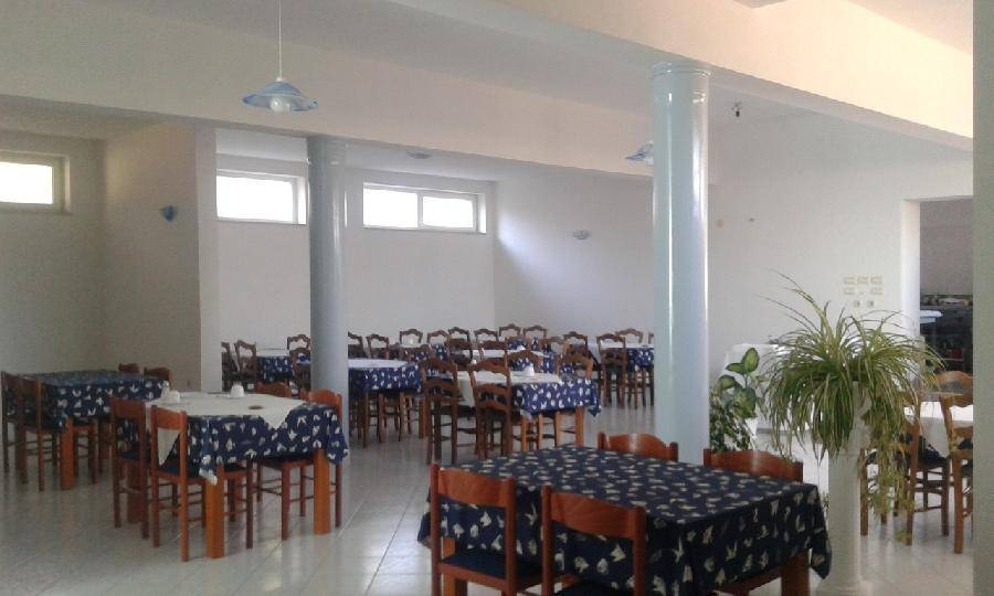Geräumiger Speisesaal mit vielen Tischen und Stühlen, bereit für Gäste, mit großen Fenstern. 