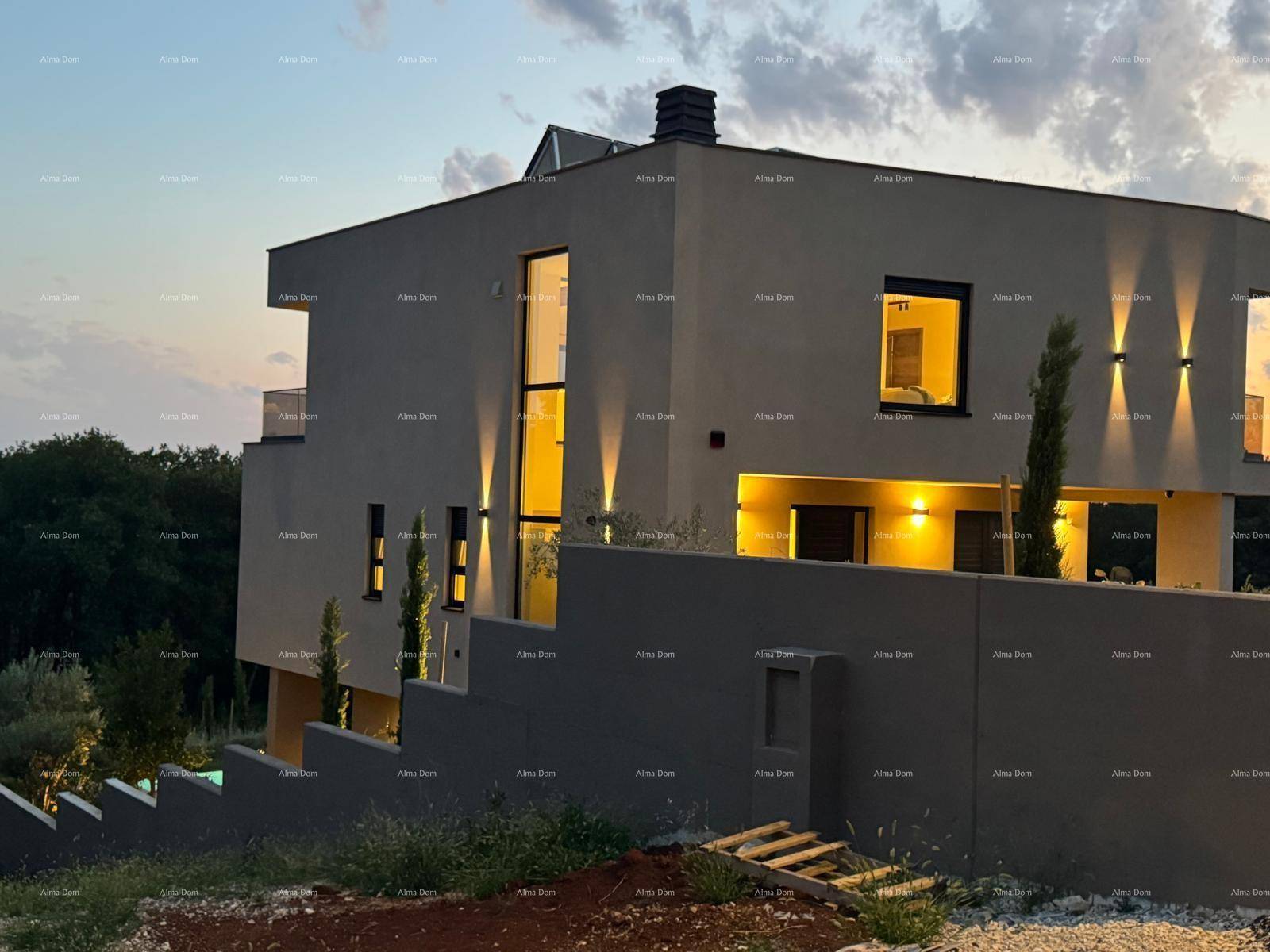 Moderne Villa bei Sonnenuntergang mit beleuchteter Fassade und großen Fenstern.