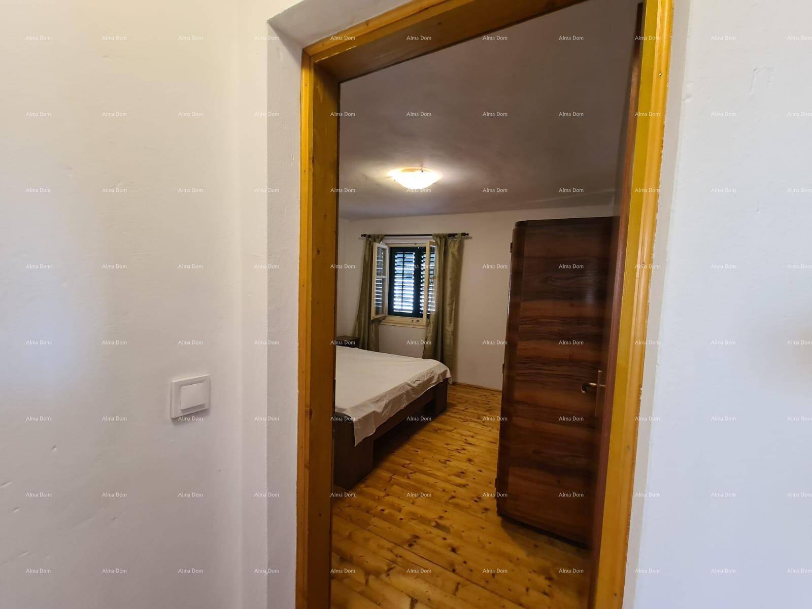 Schlafzimmer mit Holzboden, Fenster mit Fensterläden und einem Kleiderschrank, in warmen Holztönen gehalten.