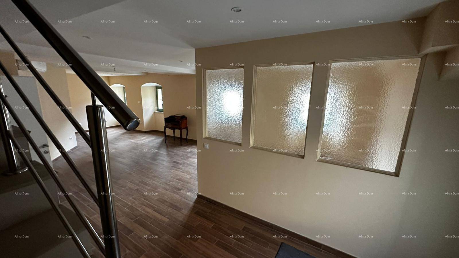 Heller Flur mit Holzfliesenboden und moderner Treppe, der zu weiteren Räumen führt.