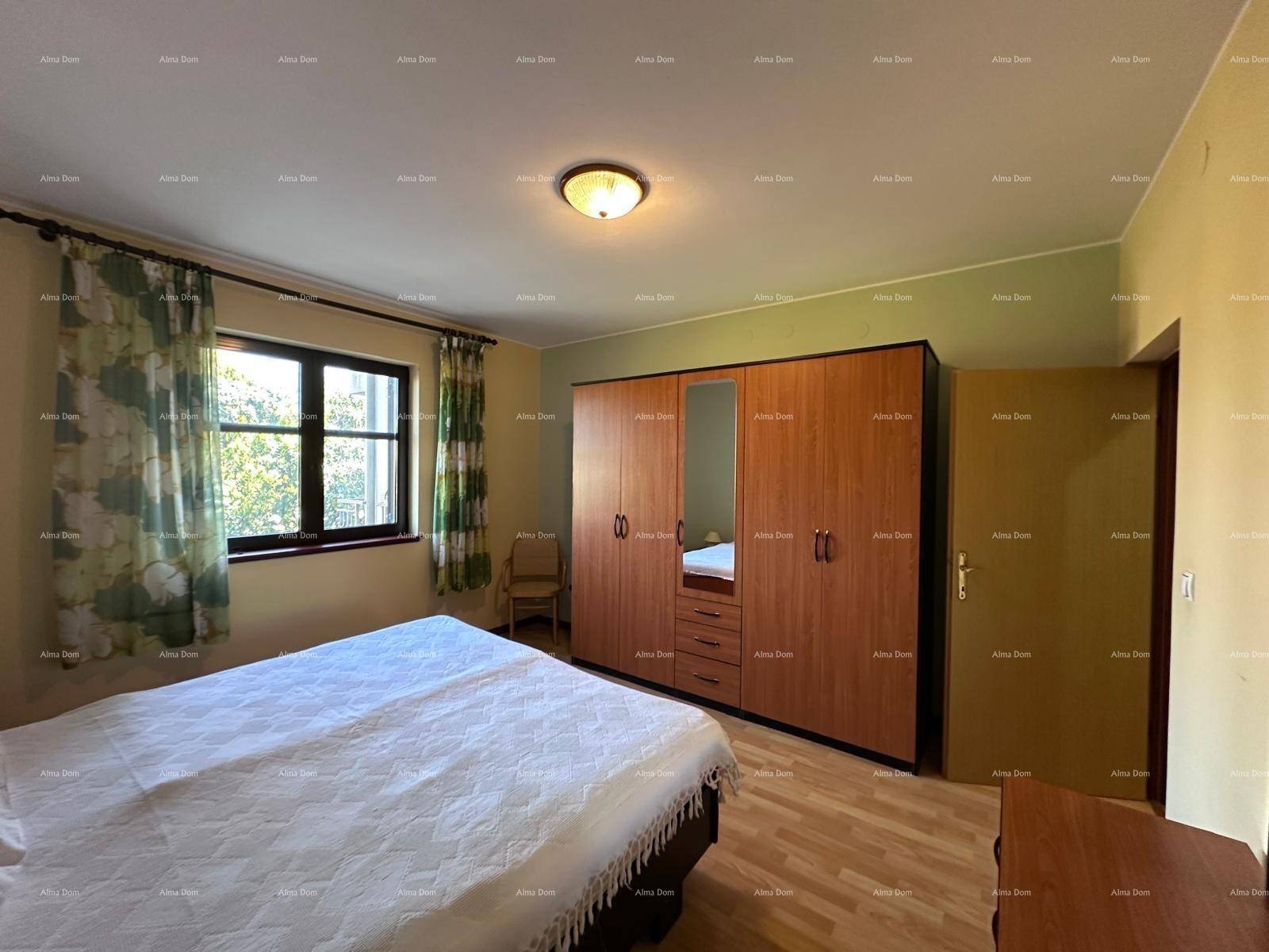 Helles Schlafzimmer mit Holzboden, großem Kleiderschrank und freundlichen grünen Wänden.