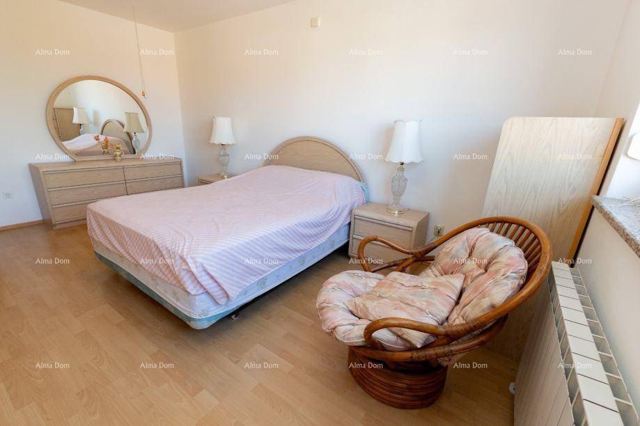 Geräumiges Schlafzimmer mit Doppelbett, Rattansessel und Blick ins Grüne.
