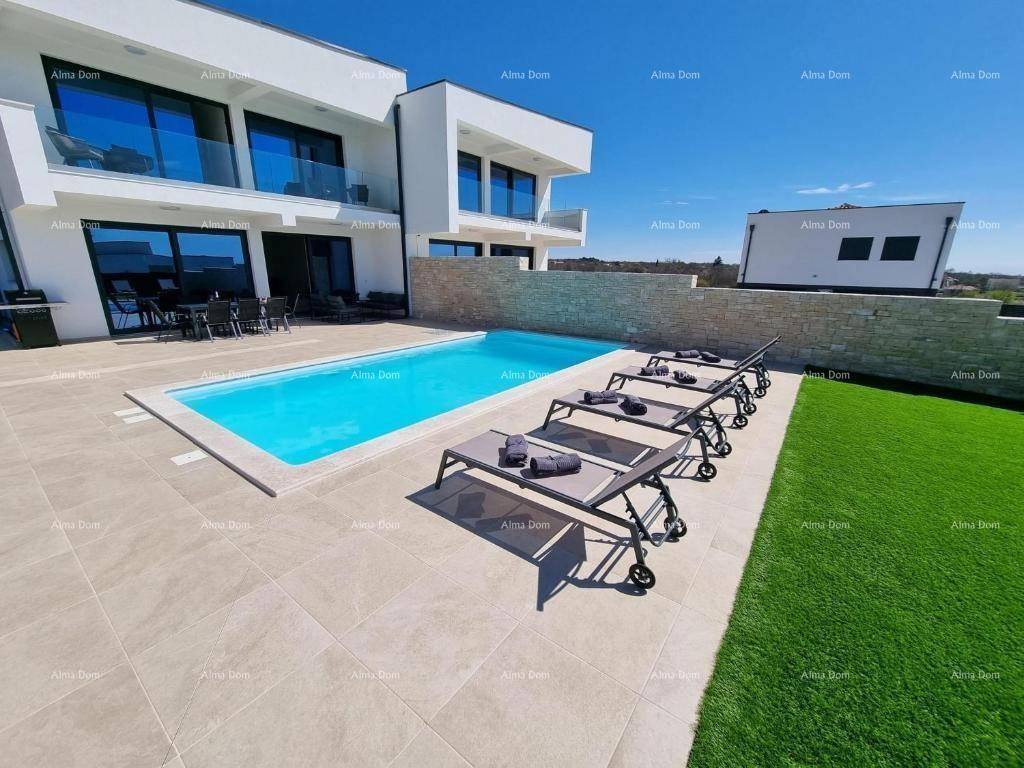 Weitläufiger Außenbereich mit Pool, Liegestühlen und gepflegtem Rasen vor der modernen Villa.