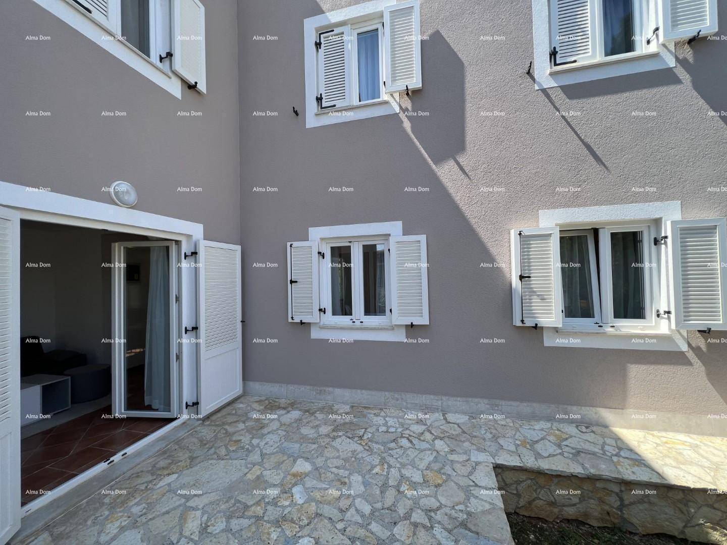 Gepflasterte Terrasse vor dem Haus mit Fensterläden und direktem Zugang zum Innenbereich.