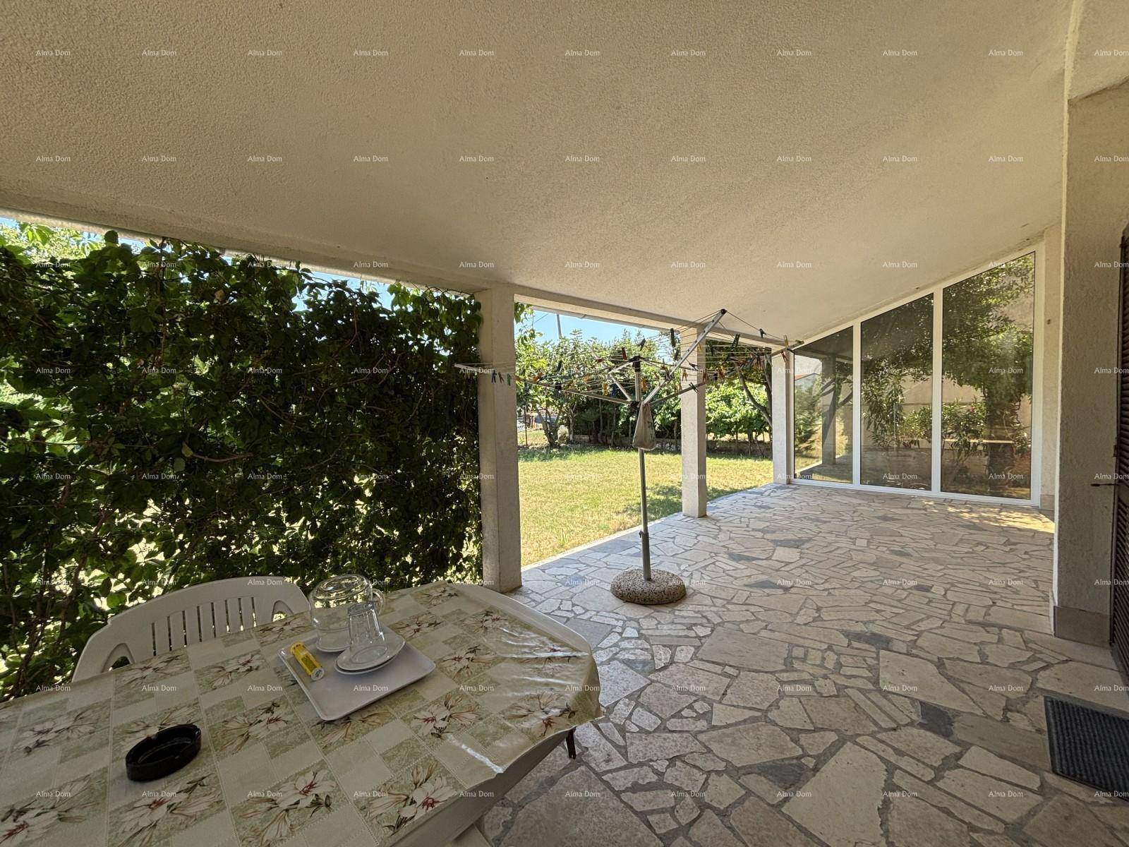 Geräumige überdachte Terrasse mit Steinfliesen und Blick auf den Garten.