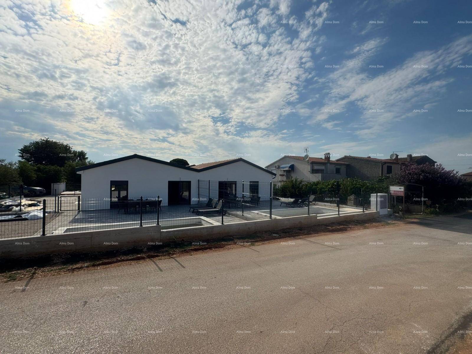 Weitläufige Ansicht des modernen Hauses mit Poolbereich unter einem bewölkten Himmel.