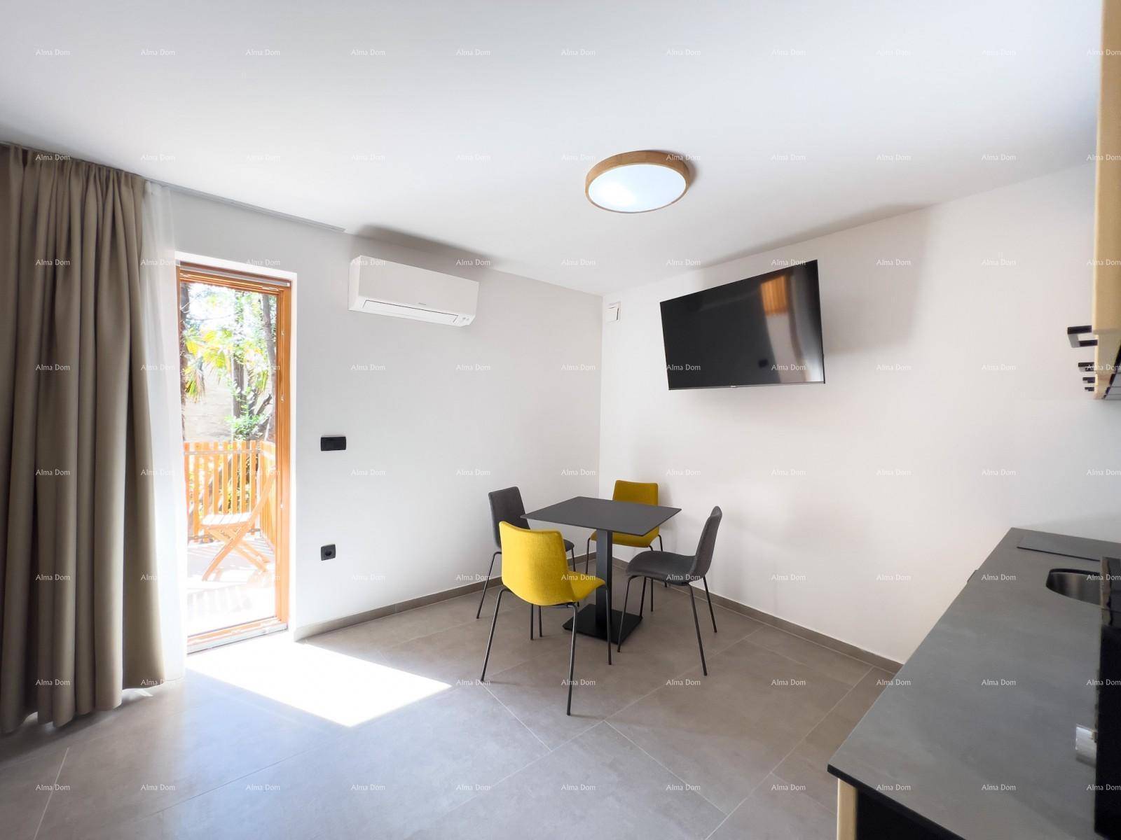 Heller Wohn- und Essbereich mit Esstisch, Wandfernseher und direktem Zugang zum Balkon.