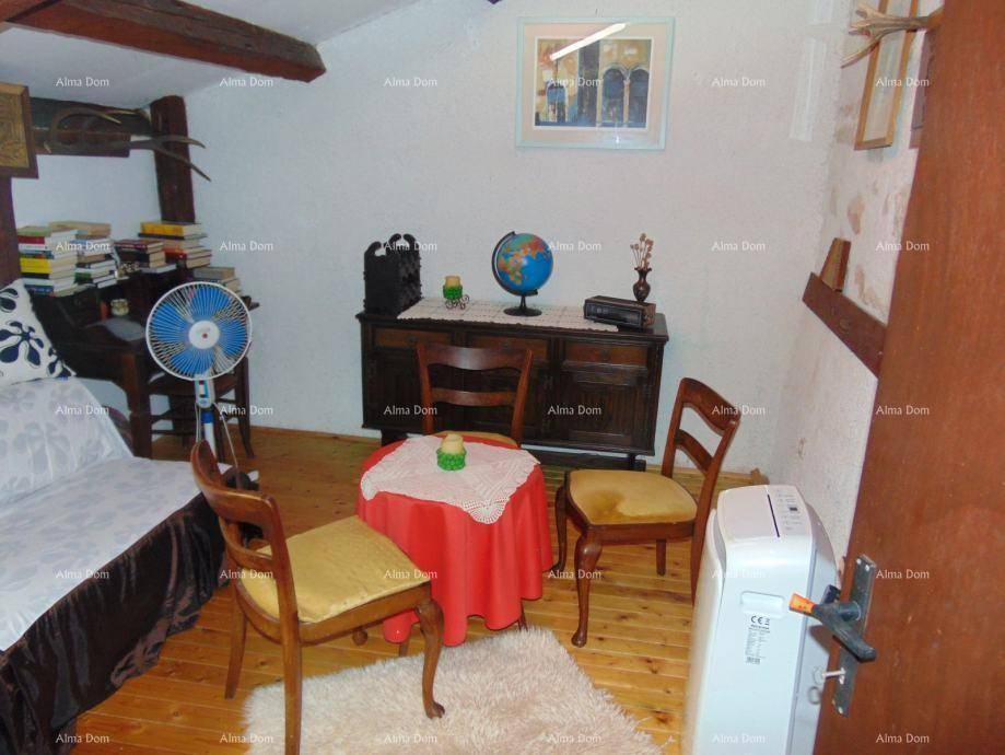 Schlafzimmer mit Holzboden, sichtbaren Deckenbalken und einem kleinen Tisch mit Stühlen.