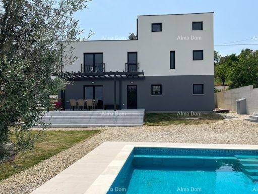 Moderne Villa mit Swimmingpool, großer Terrasse und gepflegtem Gartenbereich unter blauem Himmel.