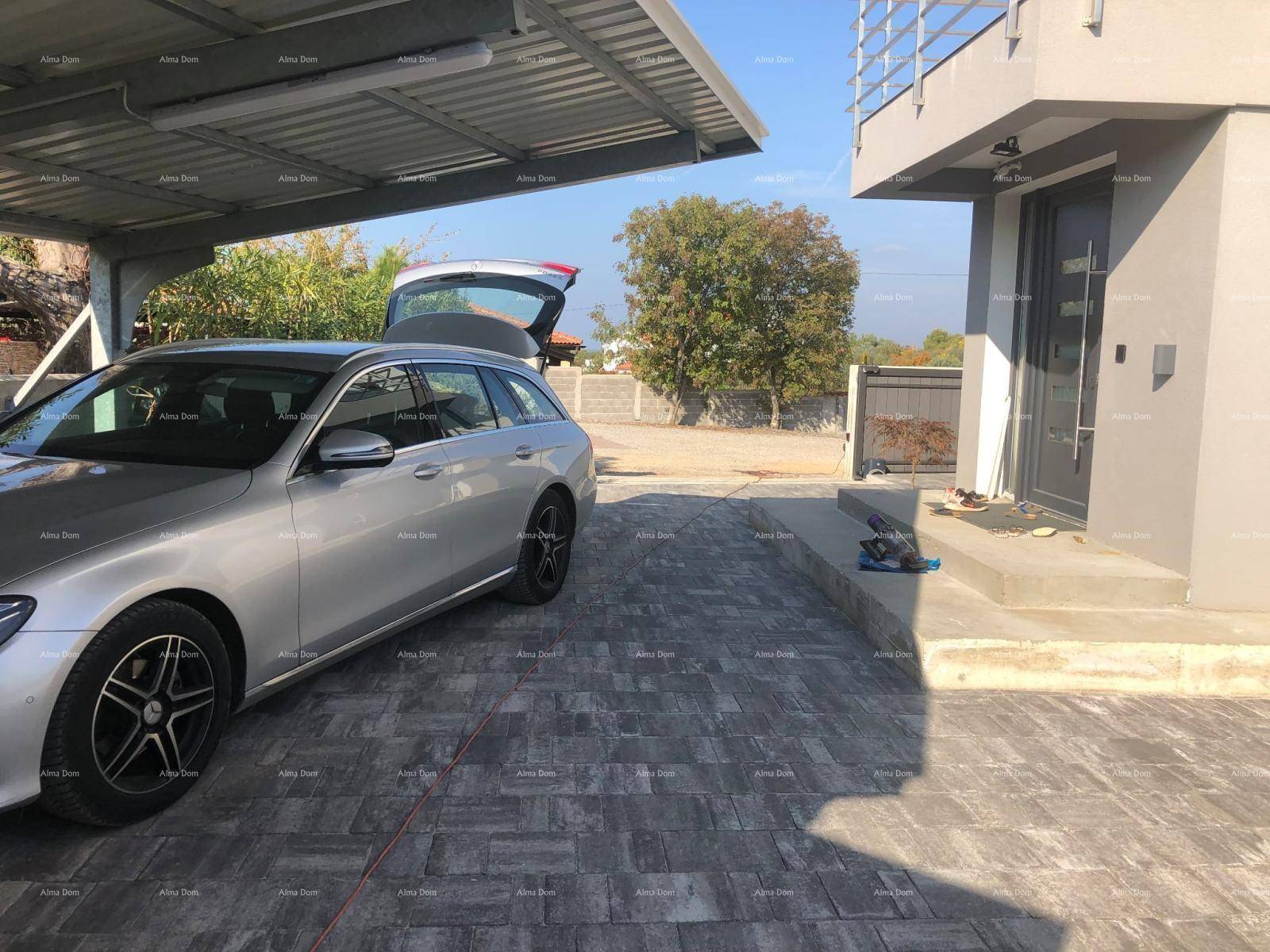 Überdachter Parkplatz mit gepflasterter Auffahrt und modernem Eingangsbereich.