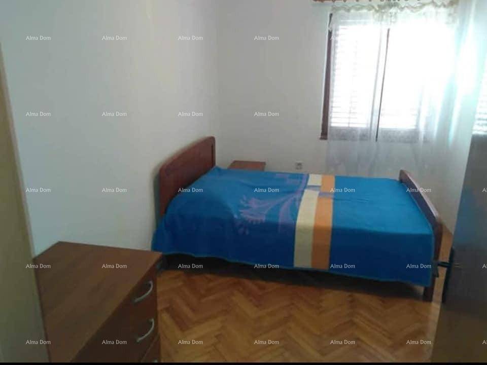 Schlafzimmer mit Holzbett, Nachttisch und Parkettboden, beleuchtet durch ein Fenster.