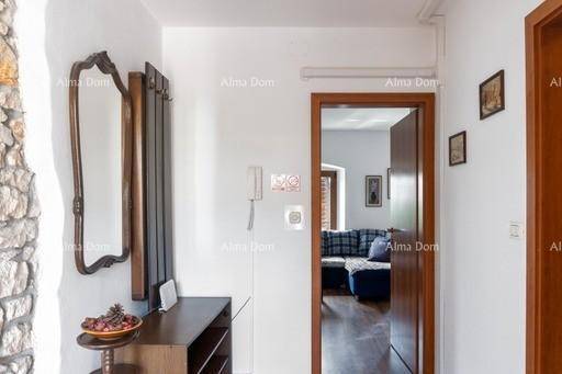 Flur mit Spiegel und Garderobe, führt zu einem Wohnbereich mit Sofa und Fenstern.