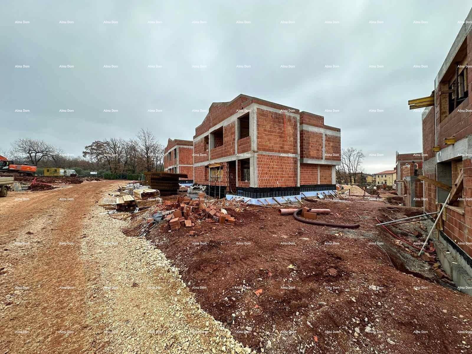 Mehrere im Rohbau befindliche Gebäude auf einer Baustelle mit Erdhügeln und Baumaterialien.