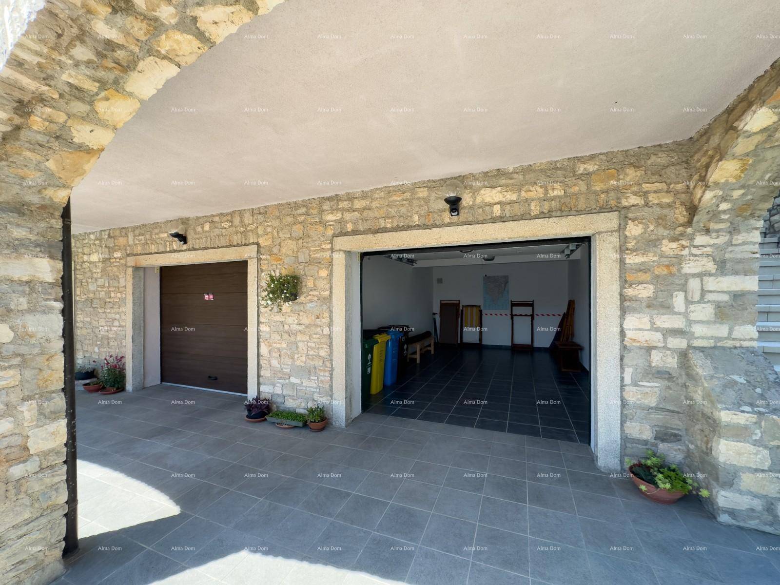 Geräumige Garage mit gefliestem Boden und zwei großen Zugängen, einer davon offen.