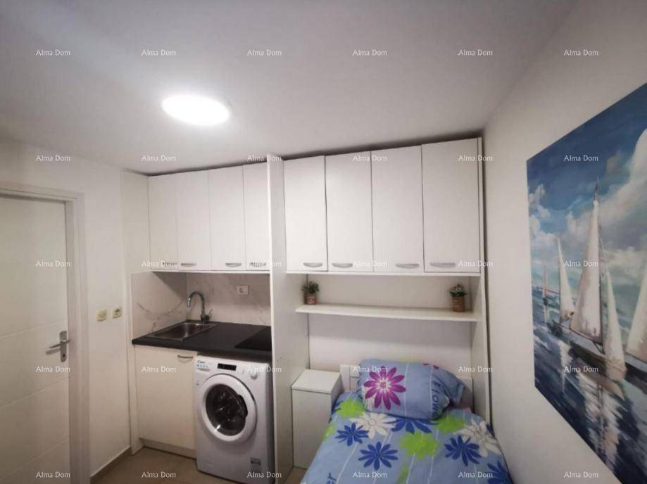 Kompaktes Schlafzimmer mit Einzelbett und integrierter Küchenzeile inklusive Waschmaschine.