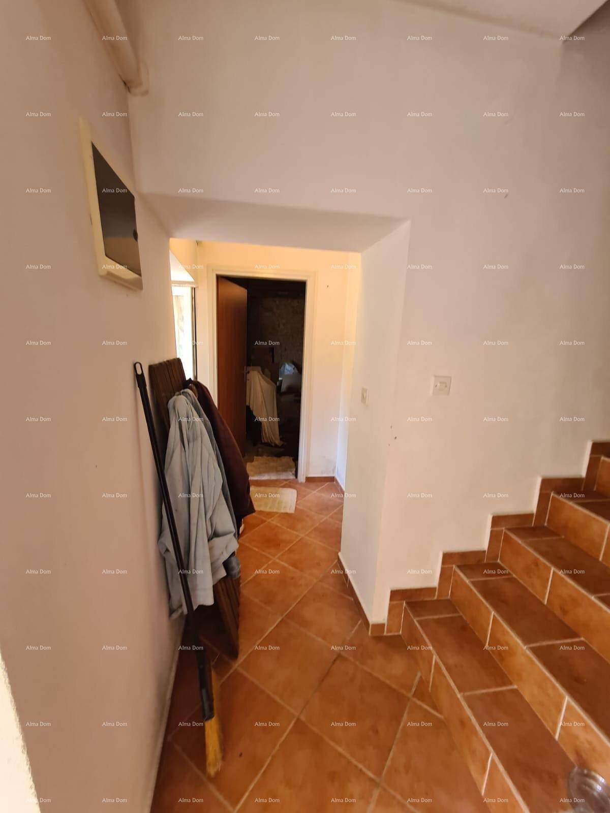 Flur mit terracottafarbenen Fliesen und einer Treppe, die in die oberen Stockwerke führt.
