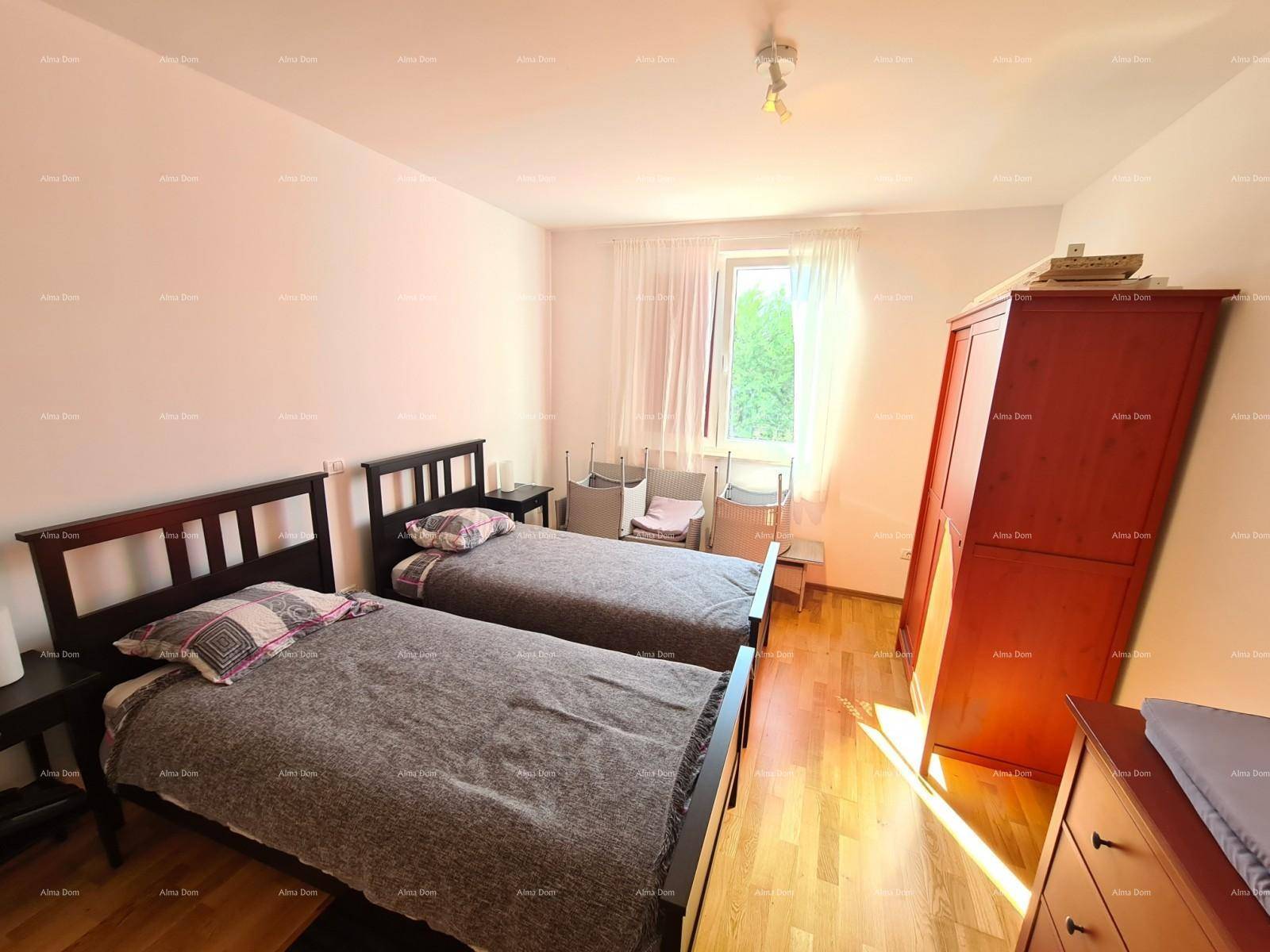 Schlafzimmer mit zwei Einzelbetten, Holzparkett und einem Fenster mit Blick ins Grüne.