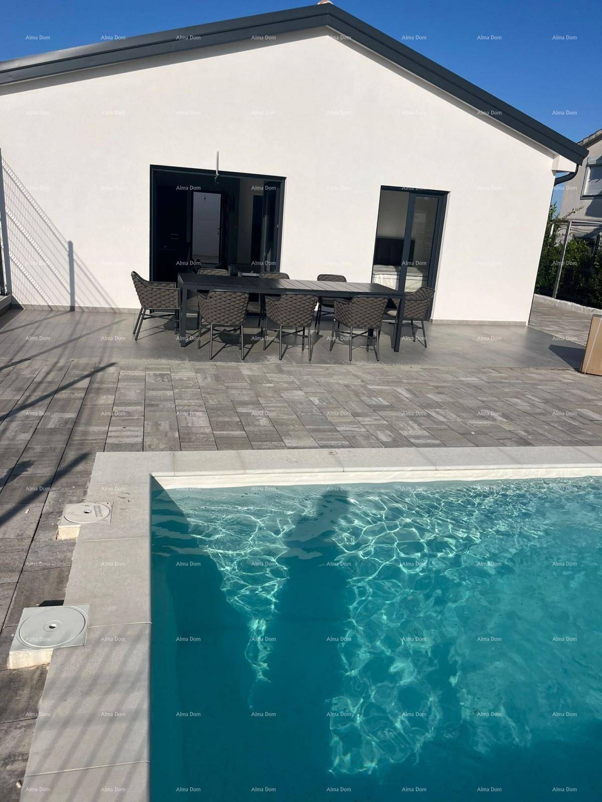 Großzügige gepflasterte Terrasse mit Esstisch und Stühlen neben dem erfrischenden Pool.