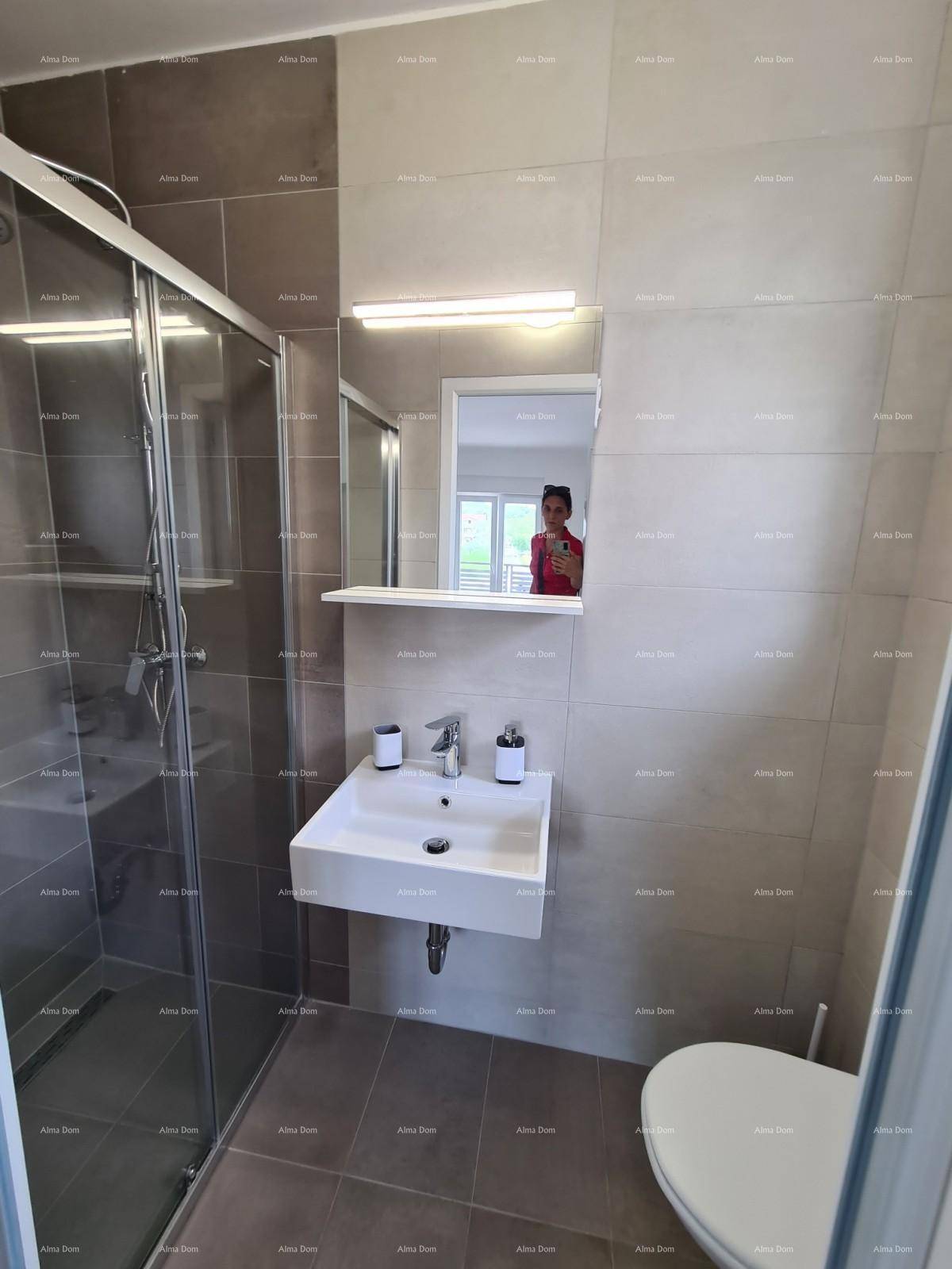 Modernes Badezimmer mit Duschkabine, wandmontiertem Waschbecken und grauen Fliesen.