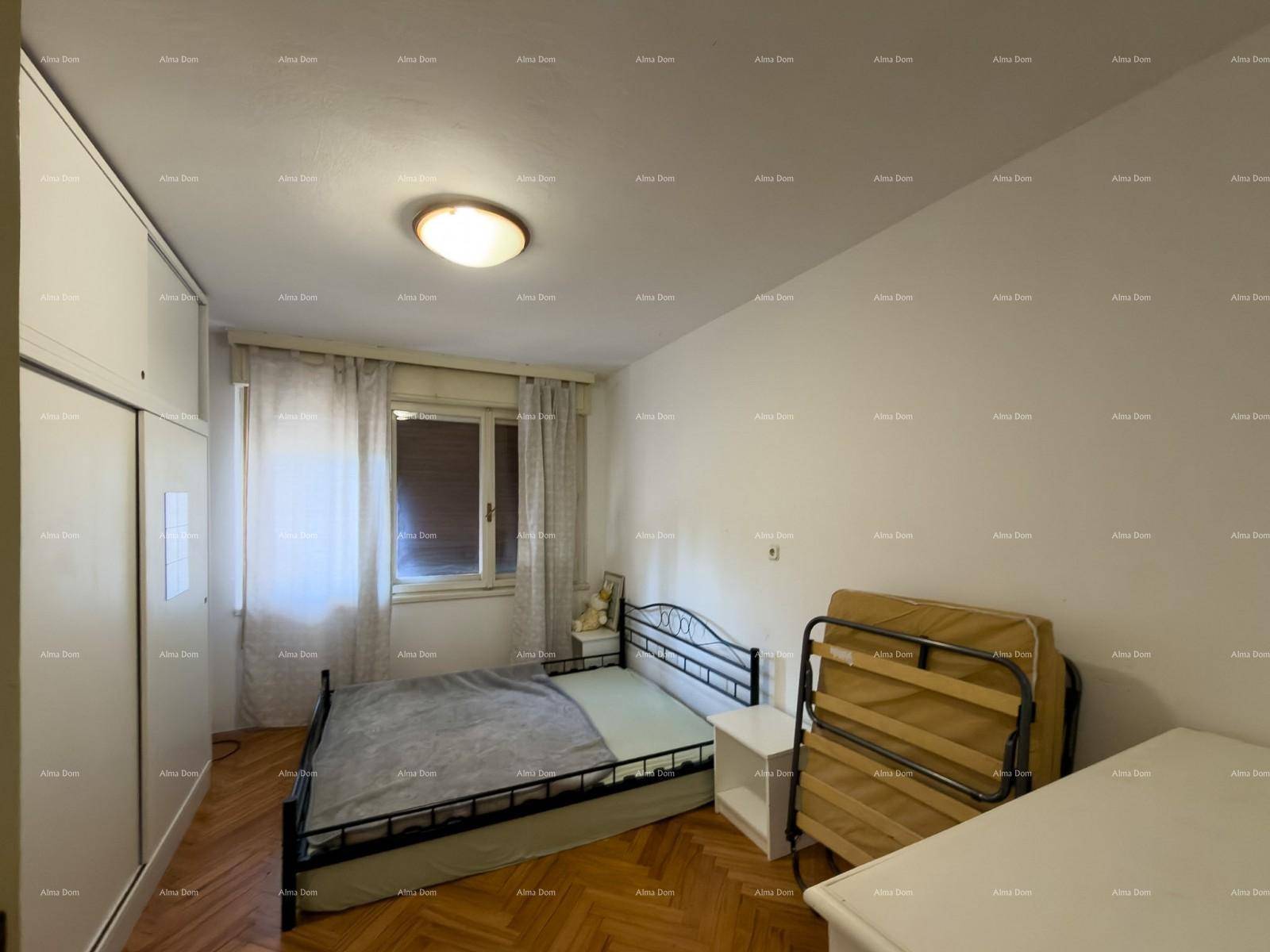 Schlafzimmer mit Holzfußboden, Fenster und einem großen weißen Kleiderschrank.