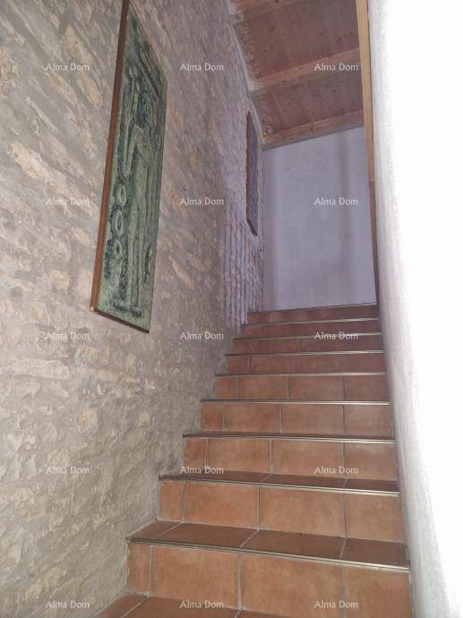 Treppenaufgang mit gefliesten Stufen, einer Steinwand und einem Holzbalken an der Decke.