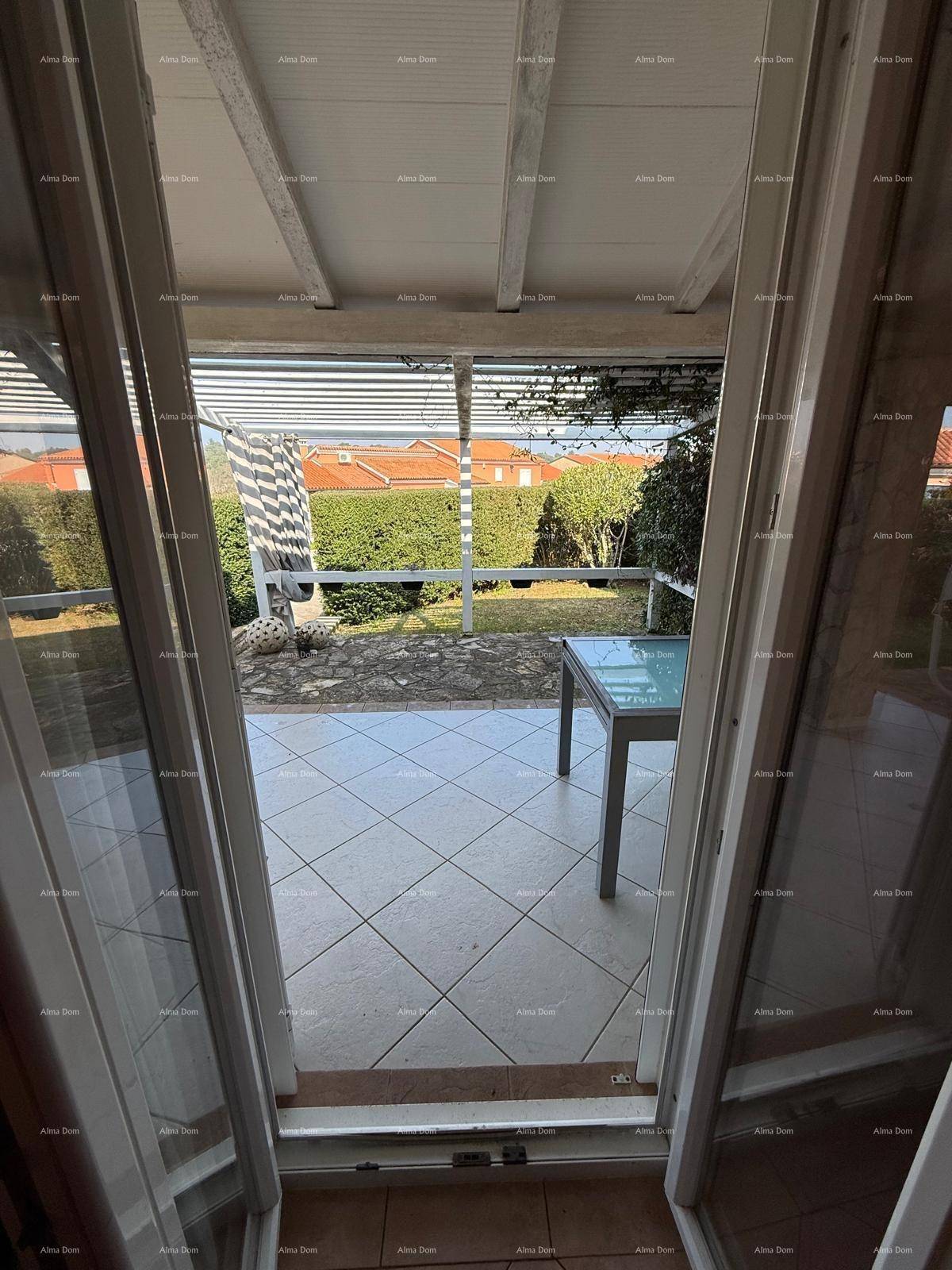 Blick von innen auf eine überdachte Terrasse mit Fliesenboden und Gartenblick.
