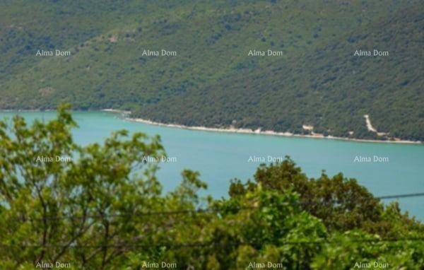 Malerischer Blick auf das blaue Meer oder einen See, umgeben von üppig grünen Hügeln und Wäldern.