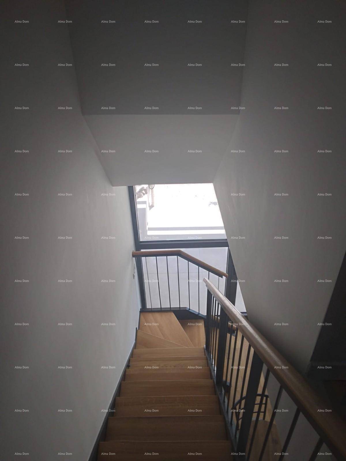 Moderne Holztreppe mit Metallgeländer und Holzhandlauf, die von oben durch ein Fenster hell beleuchtet wird.
