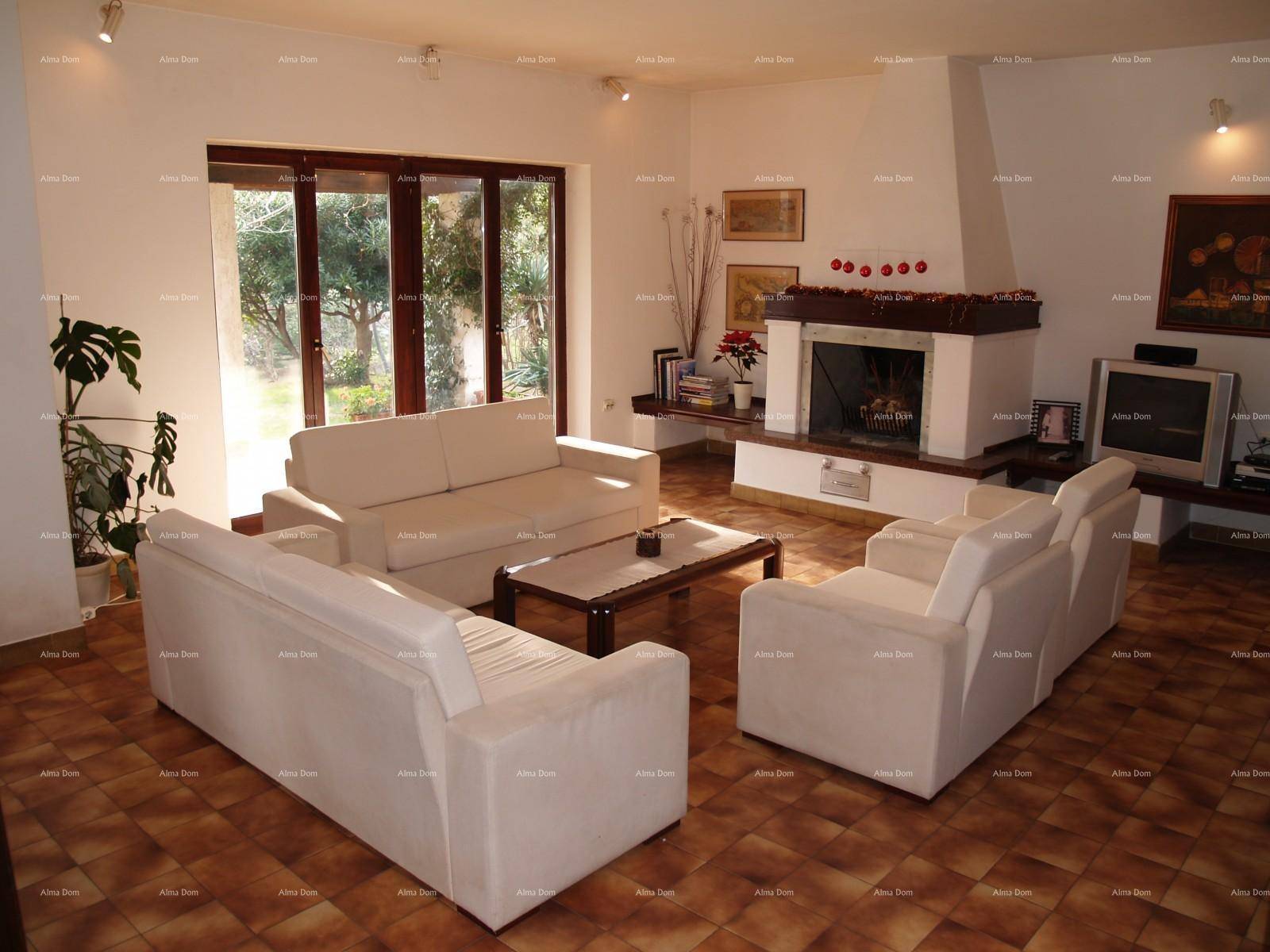 Gemütliches Wohnzimmer mit hellem Sofa, Kamin und Blick in den Garten.