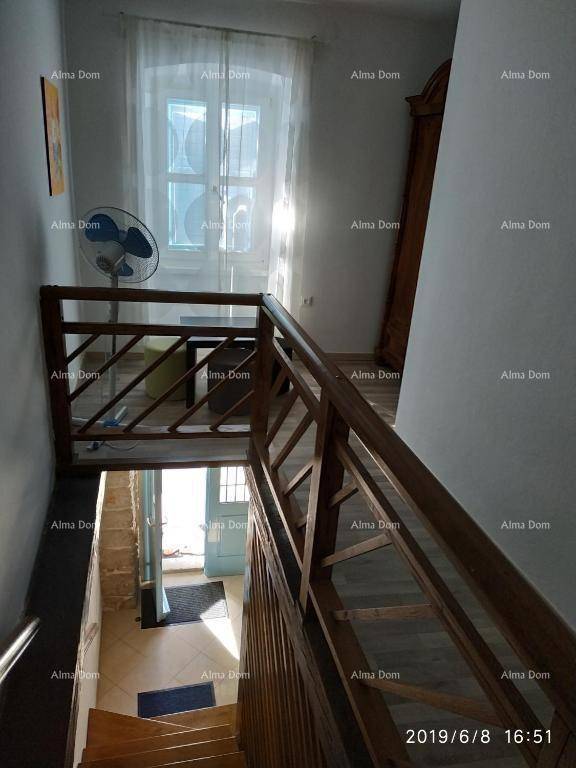 Holztreppe führt in die untere Etage, mit natürlichem Lichteinfall durch ein Fenster.