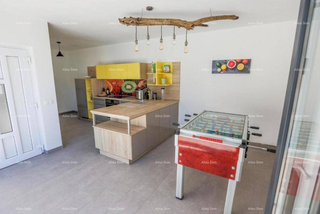 Offener Bereich mit bunter Küche, Esstisch und Tischfußball, ideal für Unterhaltung.