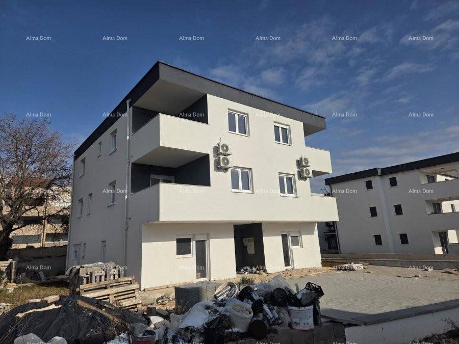 Modernes Mehrfamilienhaus mit weißer und grauer Fassade, Balkonen und Klimaanlagen im Bauzustand.