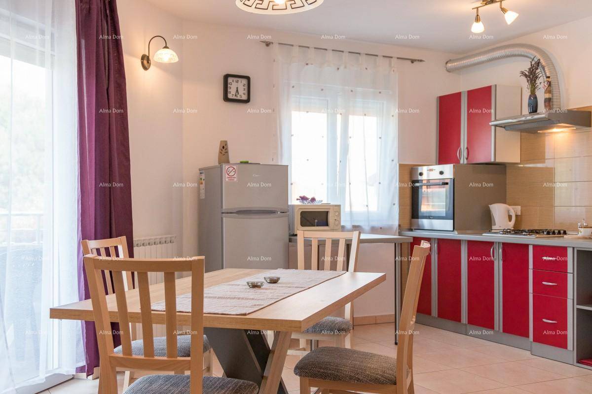 Moderne Küche mit roten Schrankfronten, Essbereich und Fenster mit lila Vorhängen.