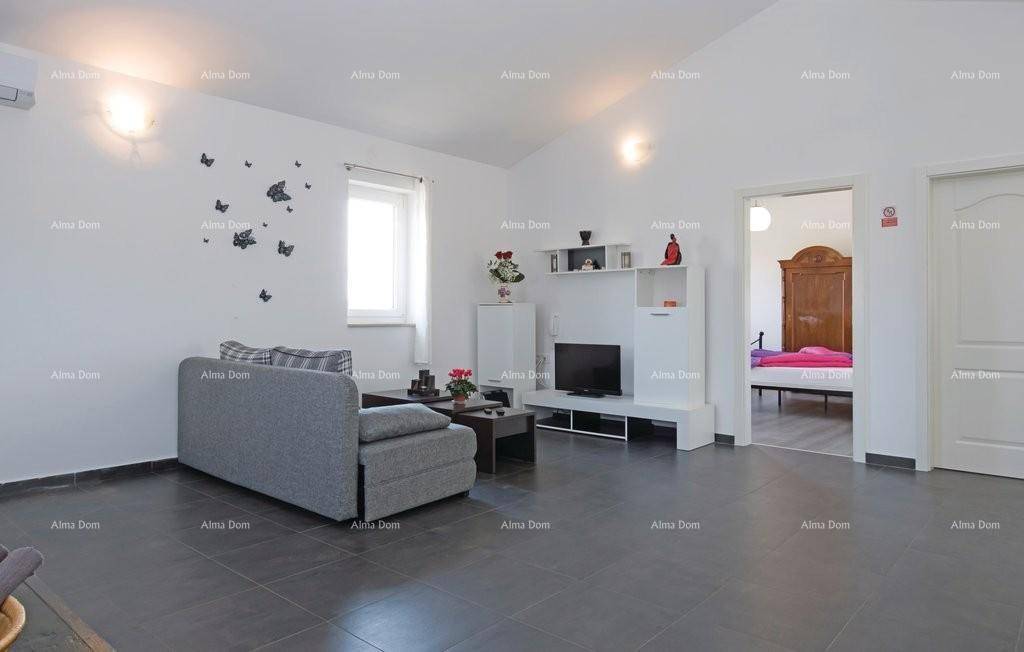 Wohnzimmer mit Sofa, Fernseher und Zugang zu einem Schlafzimmer.