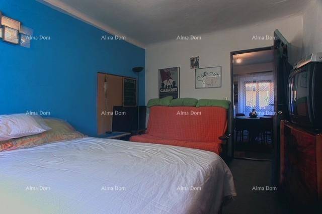Schlafzimmer mit Bett und Sofa, das durch eine Tür mit einem weiteren Wohnbereich verbunden ist.